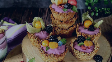 muesli cakes with coloured blueberry powder yogurt and fruits on a wooden plate