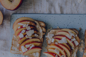 Harctic Superfoods toasts with nectarine slices, coconut flakes and energy boost elixir on a plate
