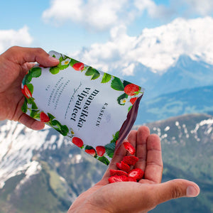 Harctic Superfoods dried berries snack with dried strawberry slices being poured on a hand out of a bag in front of snowy mountain scenery
